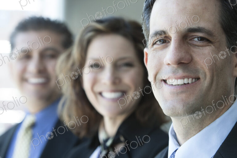 Three business people, head and shoulders, looking at camera portrait.