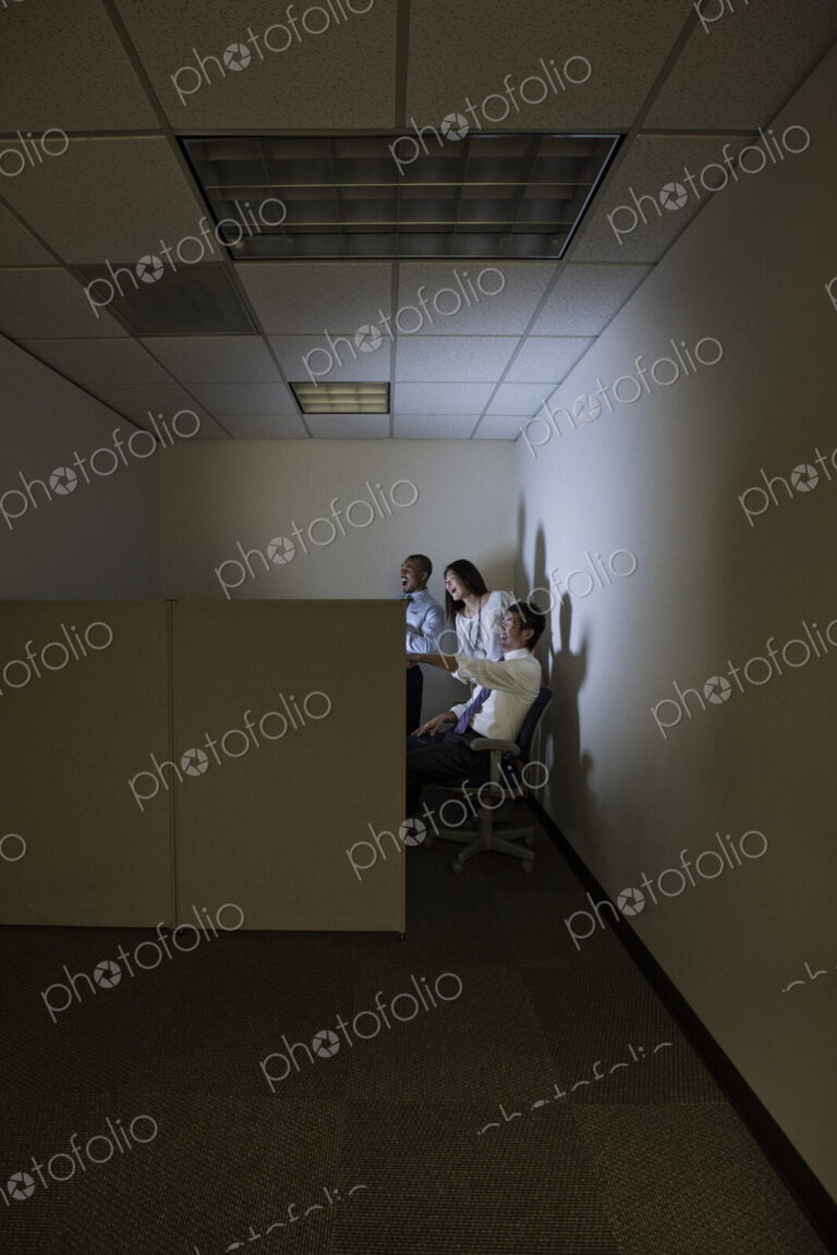 Three business people lit up by a desktop computer screen in a small corner