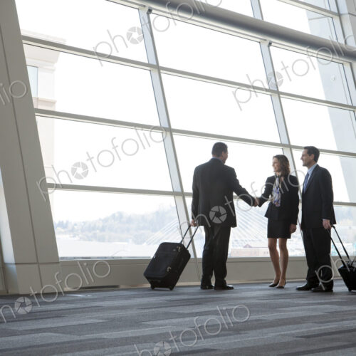 Three business people meeting in front of a large window in a conventnion center lobby.