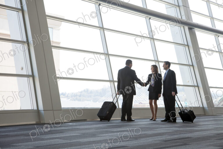 Three business people meeting in front of a large window in a conventnion center lobby.