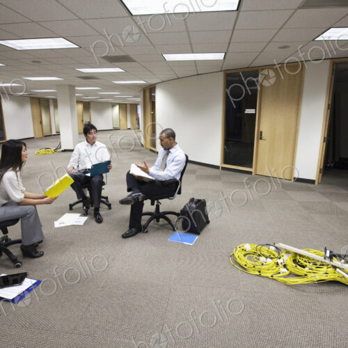 Three business people sitting making plans for a new office layout. Three business people sitting making plans for a new office layout.