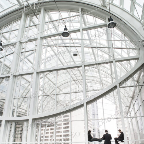 Three businesspeople meeting in front of a window in a large convention center loggy. Three businesspeople meeting in front of a window in a large convention center loggy.