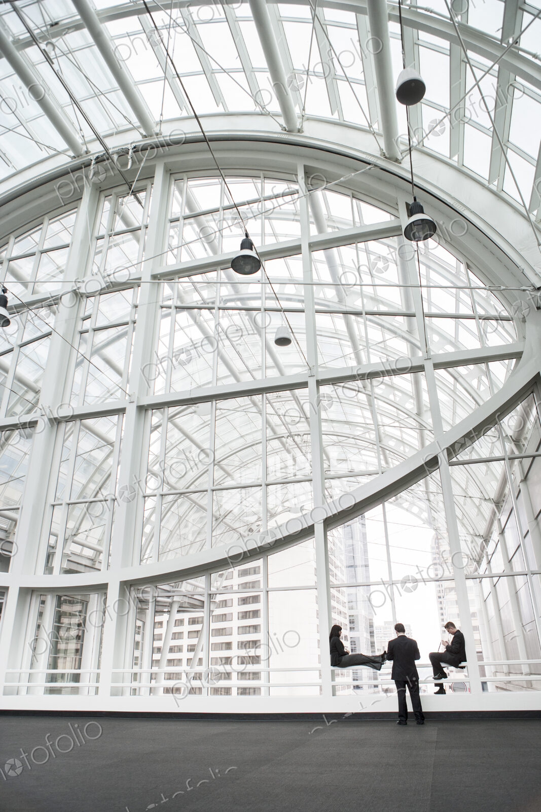 Three businesspeople meeting in front of a window in a large convention center loggy.
