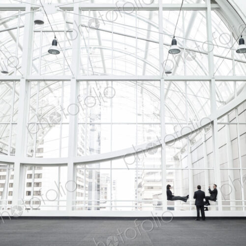 Three businesspeople meeting in front of a window in a large convention center loggy.