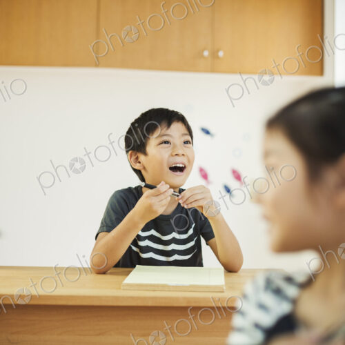 Three children, a boy and two girls in a classroom.