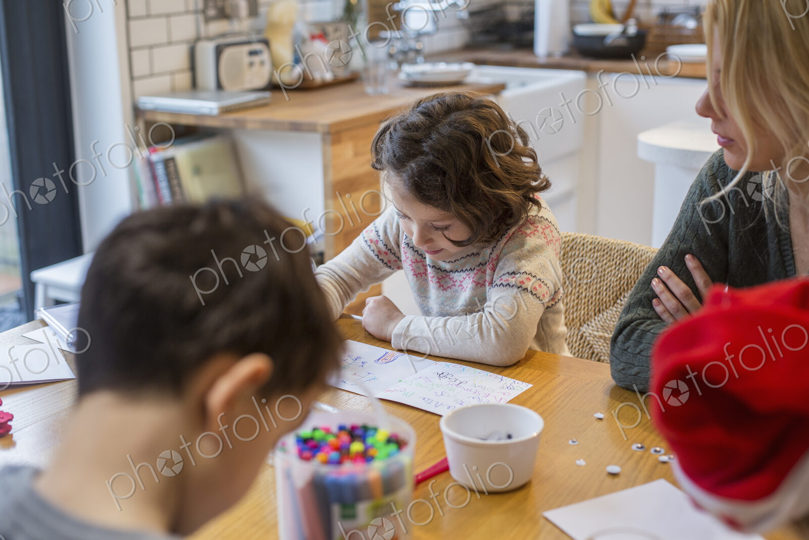 Three children and an adult woman at a table, drawing and writing cards and letters to…
