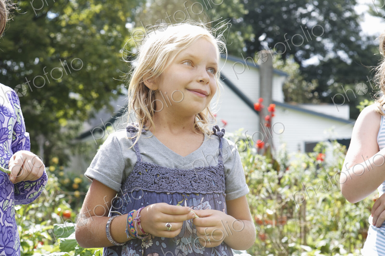 Three children in a garden, picking vegetables.
