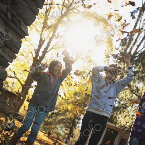 Three children in the autumn sunshine. Playing outdoors throwing the fallen leaves in… Three children in the autumn sunshine. Playing outdoors throwing the fallen leaves in…