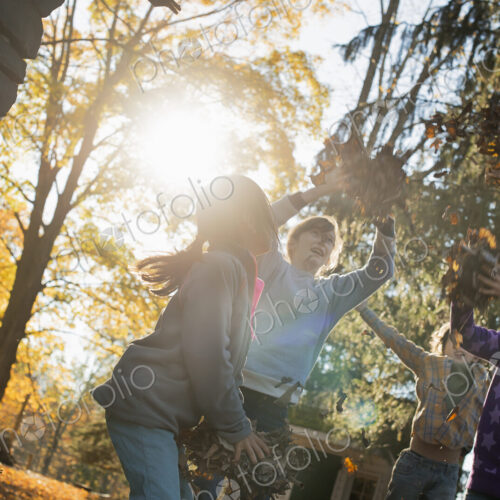 Three children in the autumn sunshine. Playing outdoors throwing the fallen leaves in… Three children in the autumn sunshine. Playing outdoors throwing the fallen leaves in…