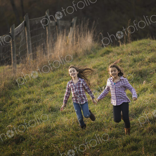 Three children running down a hill on an organic farm. Three children running down a hill on an organic farm.