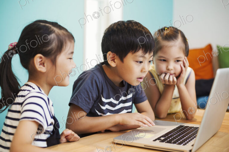 Three children using a laptop, two girls and a boy.