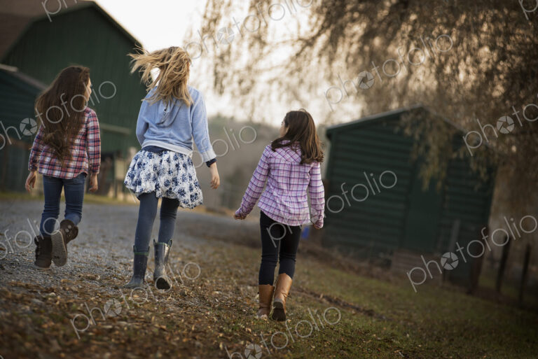 Three children walking along a path on an organic farm.