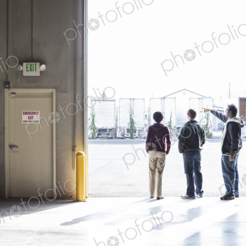 Three employees waiting for a product delivery in a loading dock door at a warehouse. Three employees waiting for a product delivery in a loading dock door at a warehouse.