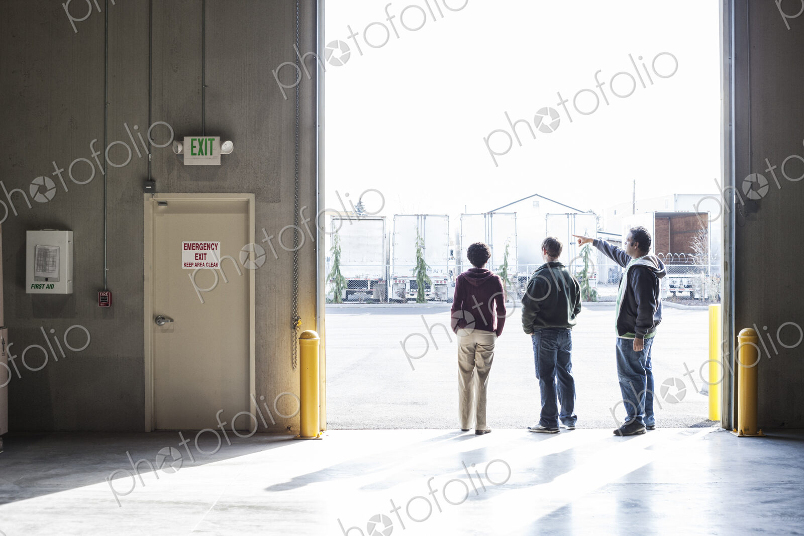 Three employees waiting for a product delivery in a loading dock door at a warehouse.