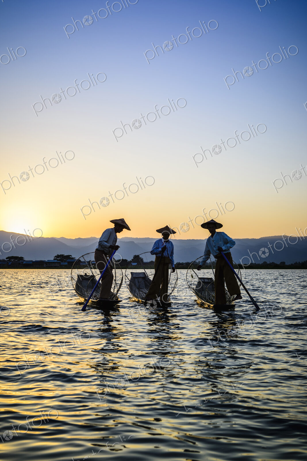 Three fishermen on Lake Inles, standing in their traditional boats.
