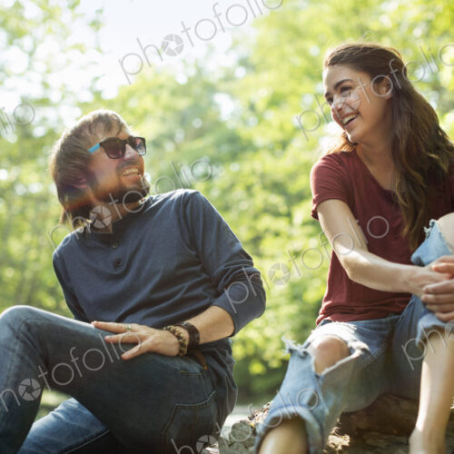 Three friends by the riverbank laughing.