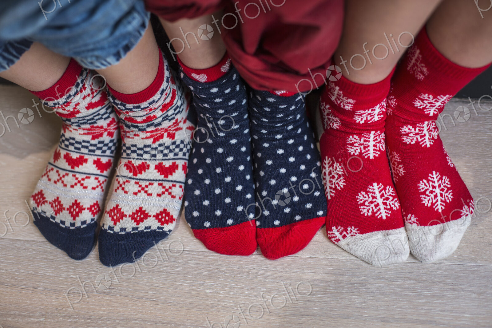 Three pairs of children’s feet in bright patterned Christmas socks.