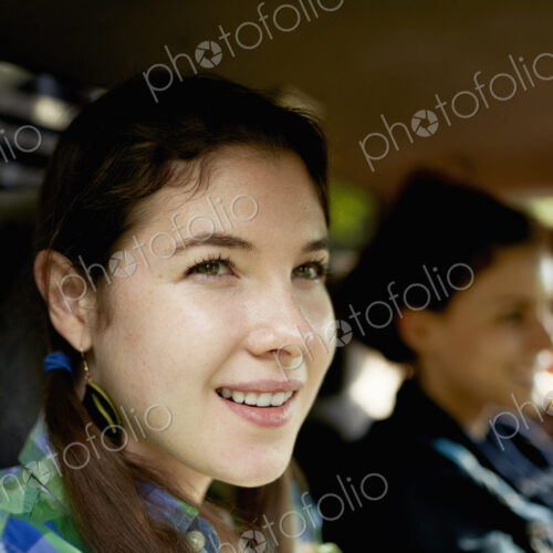 Three passengers in the cab of a pickup truck. One young man driving. Two young women…