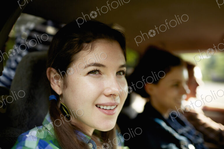 Three passengers in the cab of a pickup truck. One young man driving. Two young women…