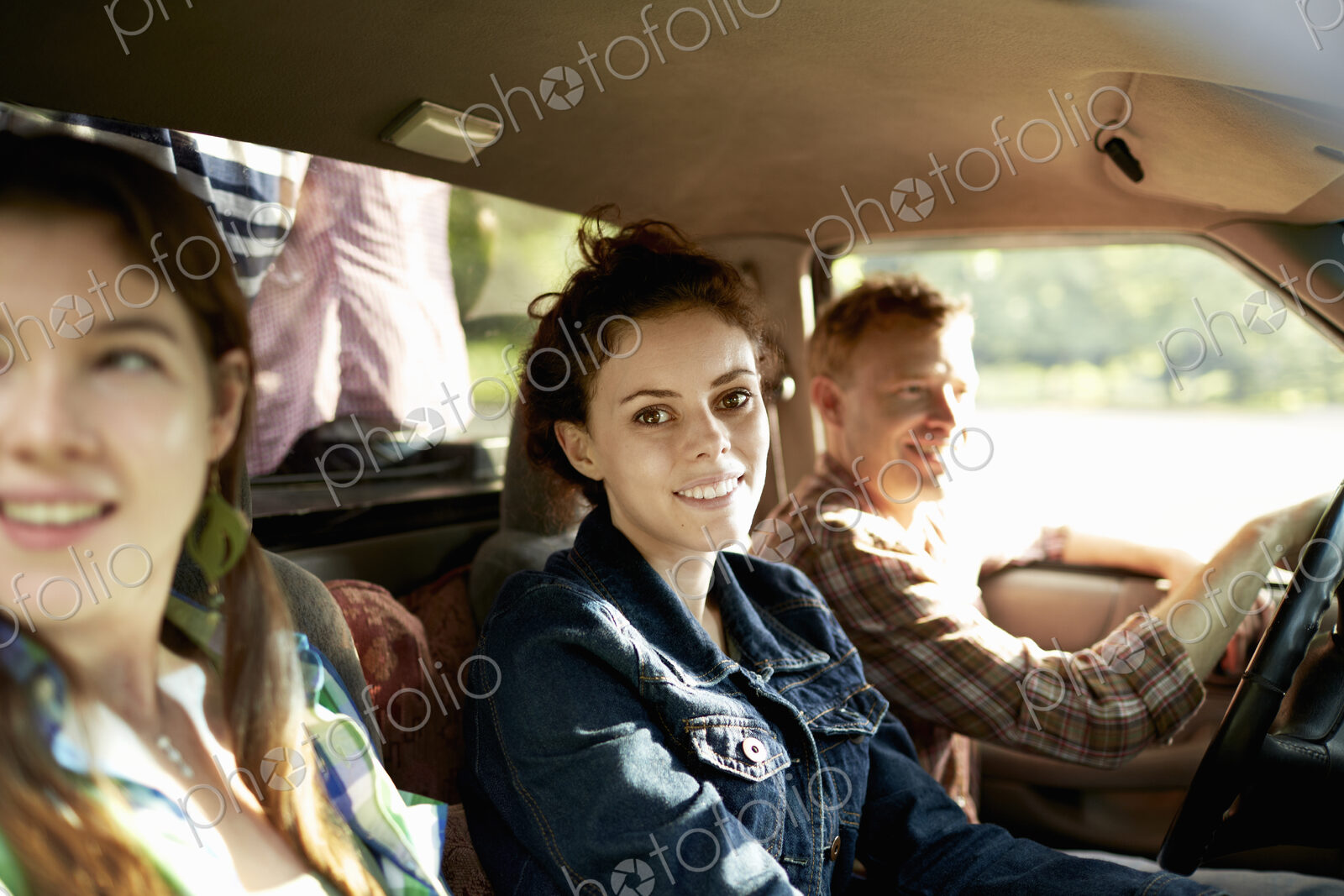 Three passengers in the cab of a pickup truck. One young man driving. Two young women…