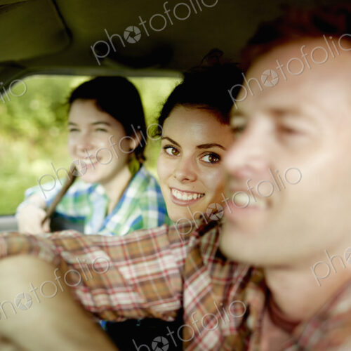 Three passengers in the cab of a pickup truck. One young man driving. Two young women…