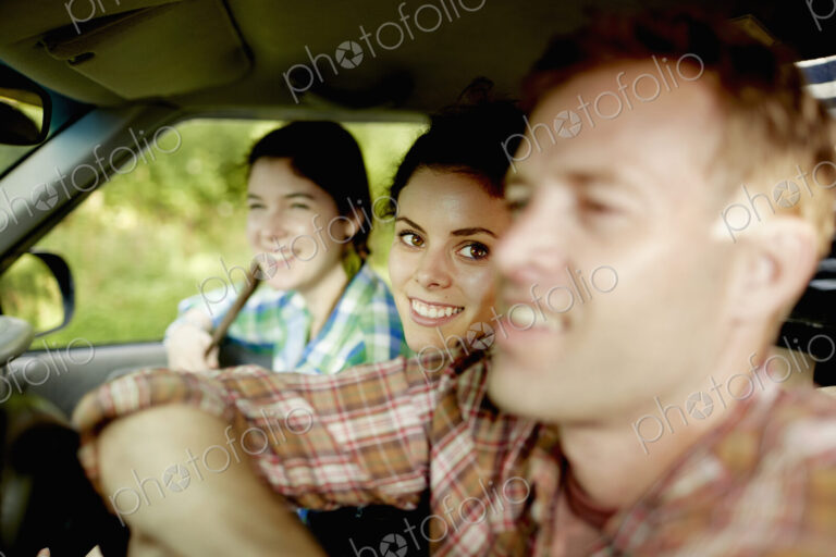 Three passengers in the cab of a pickup truck. One young man driving. Two young women…