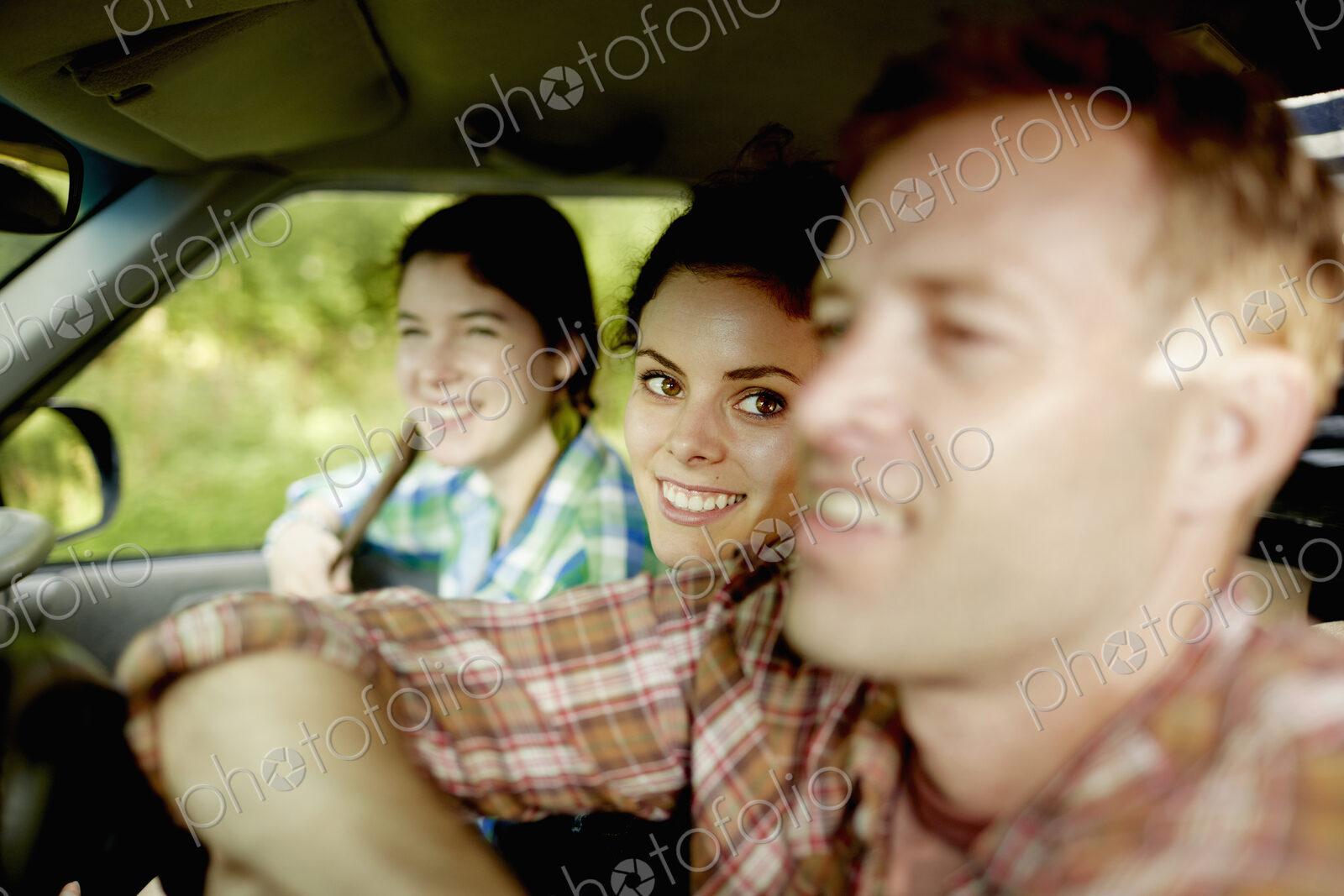 Three passengers in the cab of a pickup truck. One young man driving. Two young women…