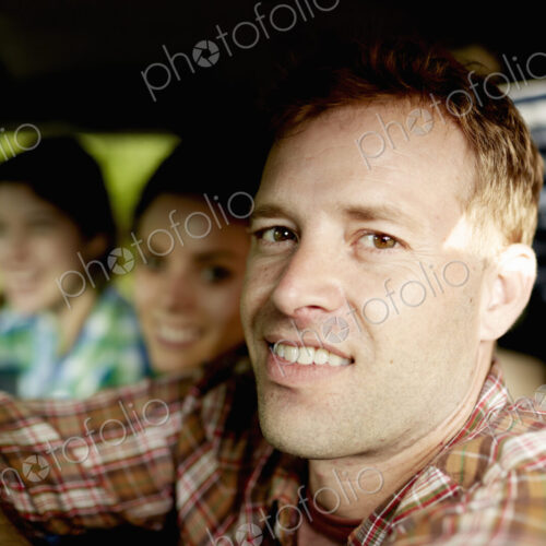 Three passengers in the cab of a pickup truck. One young man driving. Two young women…