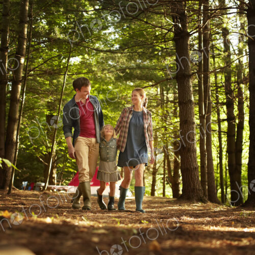 Three people, a family walking in woodland in the late afternoon. Three people, a family walking in woodland in the late afternoon.