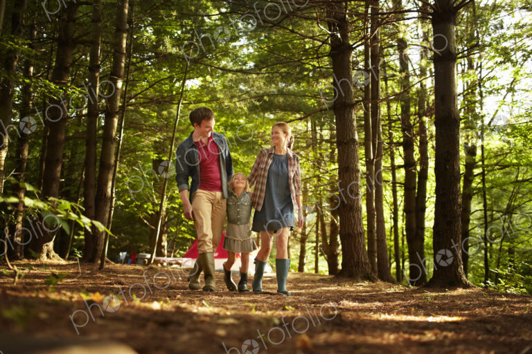 Three people, a family walking in woodland in the late afternoon.
