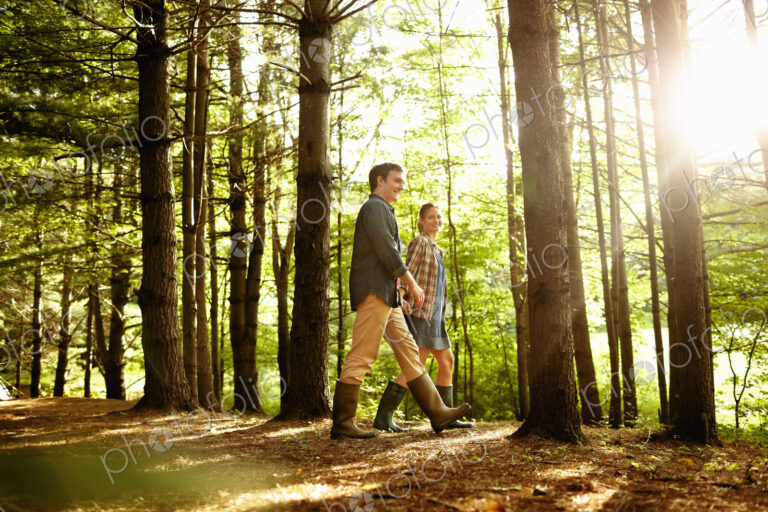 Three people, a family walking in woodland in the late afternoon.
