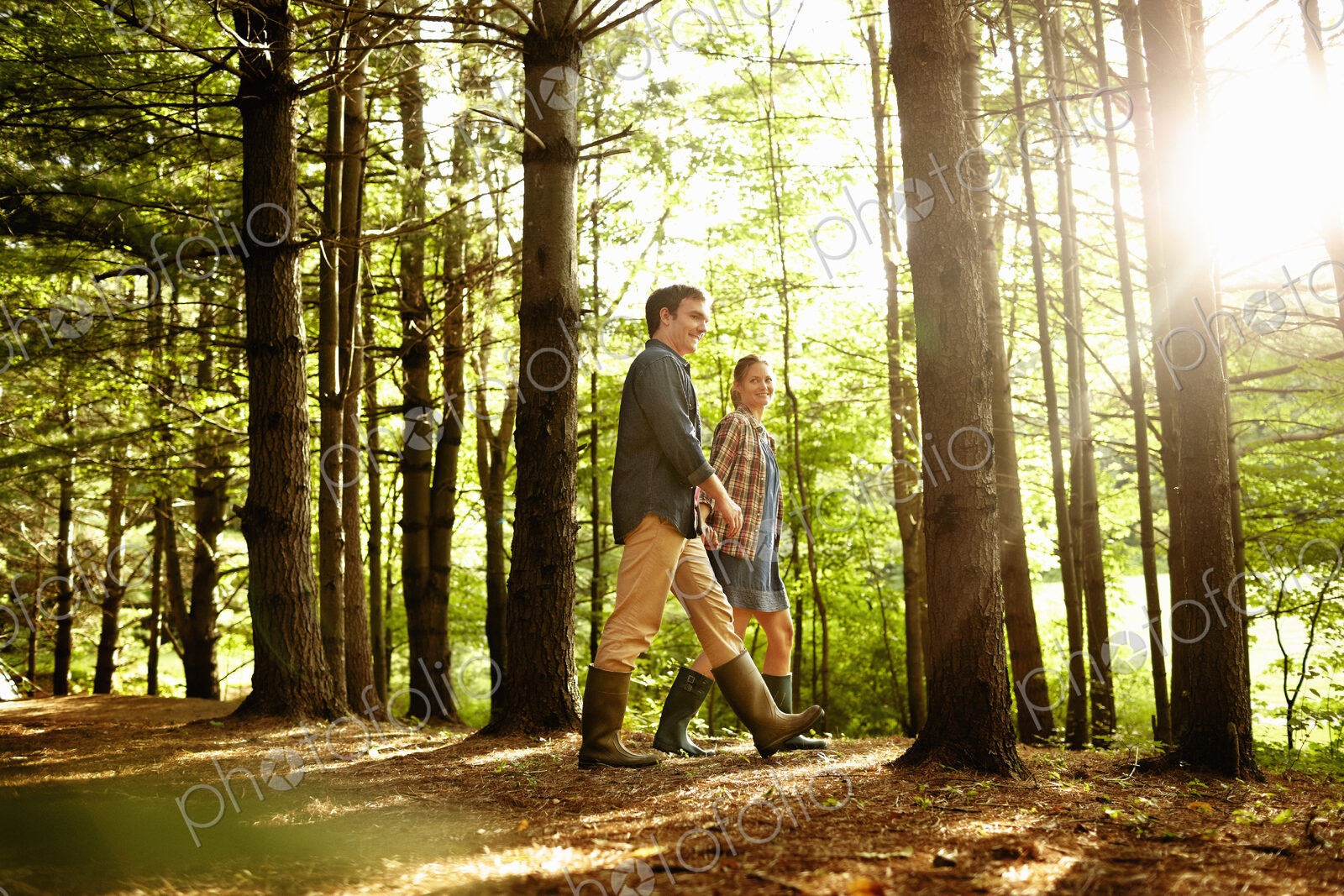 Three people, a family walking in woodland in the late afternoon.