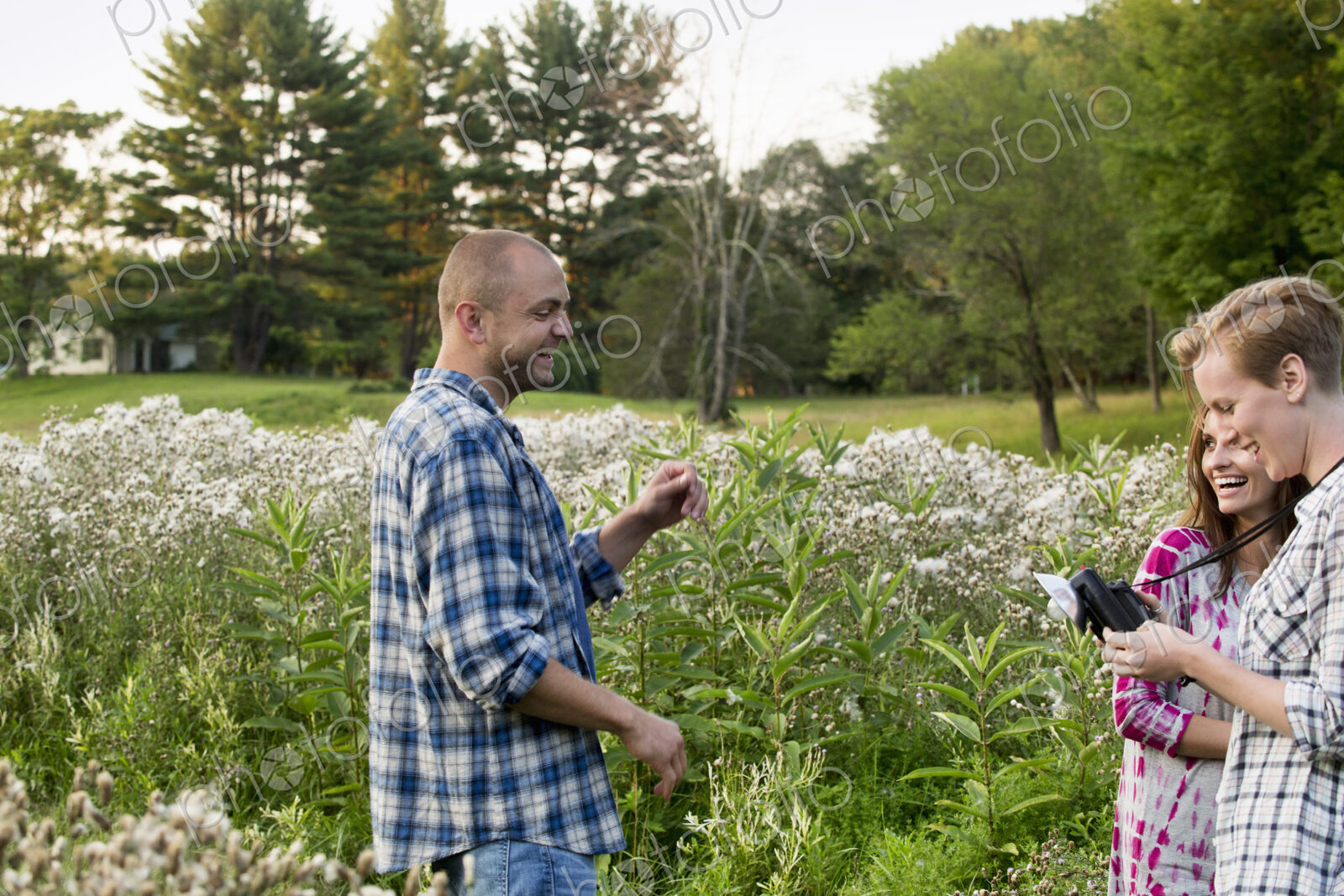Three people, a man and two women in a wildflower meadow.