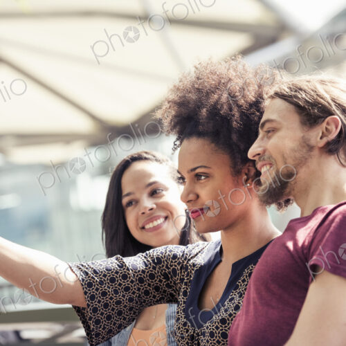Three people, a man and two women, taking selfies in a city park Three people, a man and two women, taking selfies in a city park