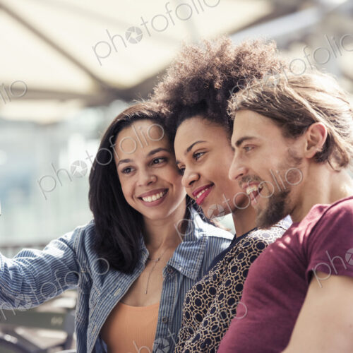 Three people, a man and two women, taking selfies in a city park Three people, a man and two women, taking selfies in a city park