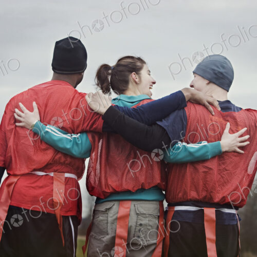 Three people, a woman and two men, getting ready for an American Flag Football game.… Three people, a woman and two men, getting ready for an American Flag Football game.…