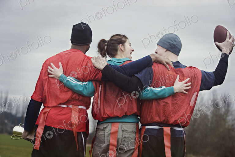 Three people, a woman and two men, getting ready for an American Flag Football game.…