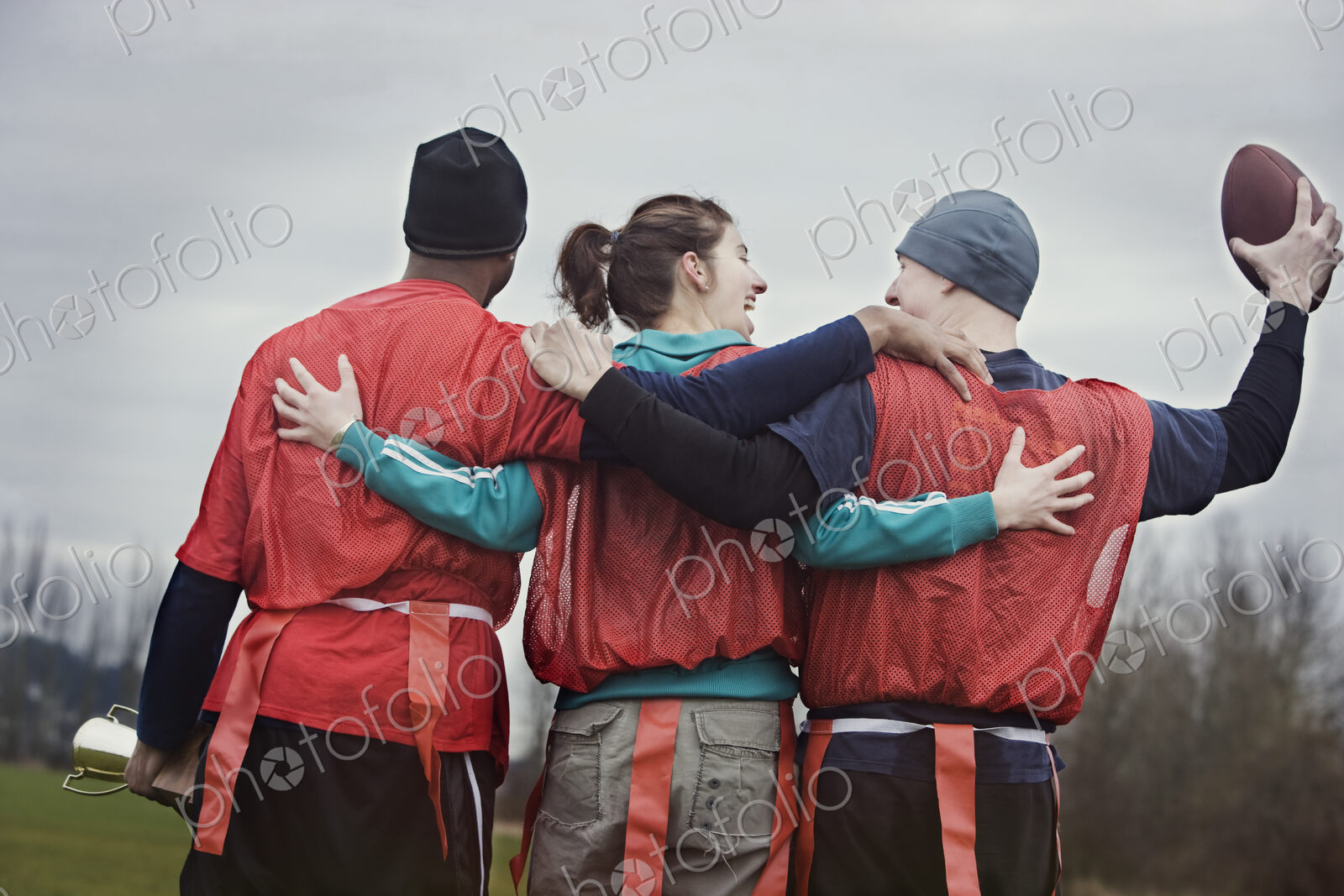 Three people, a woman and two men, getting ready for an American Flag Football game.…