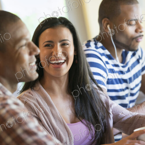 Three people in a room, one wearing headphones and two in conversation. Three people in a room, one wearing headphones and two in conversation.