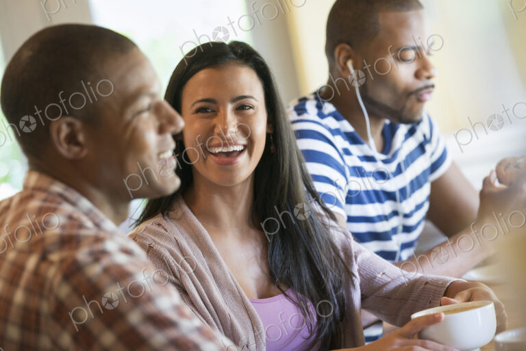 Three people in a room, one wearing headphones and two in conversation.