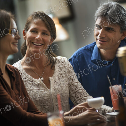 Three people meeting for a drink. Two women and a man sitting at a bar. Friends… Three people meeting for a drink. Two women and a man sitting at a bar. Friends…