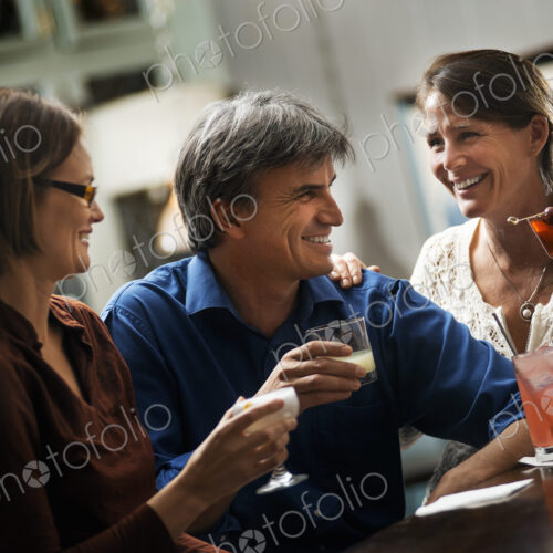 Three people meeting for a drink. Two women and a man sitting at a bar. Friends… Three people meeting for a drink. Two women and a man sitting at a bar. Friends…