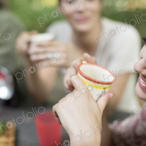 Three people seated around a wooden table outdoors in woodland sharing a meal. Three people seated around a wooden table outdoors in woodland sharing a meal.