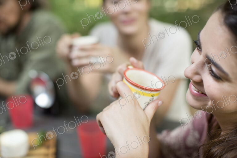 Three people seated around a wooden table outdoors in woodland sharing a meal.