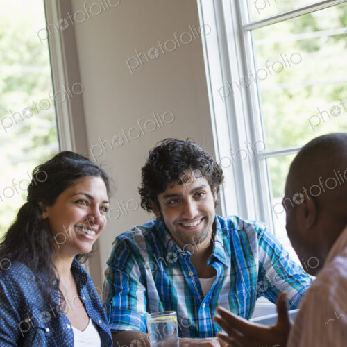 Three people seated at a cafe table talking. Three people seated at a cafe table talking.