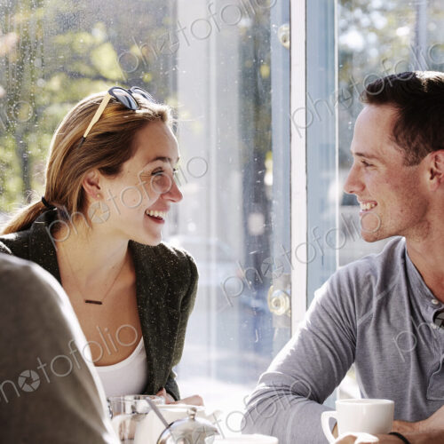 Three people sitting at a table talking, with mugs and jars of smoothies. Three people sitting at a table talking, with mugs and jars of smoothies.