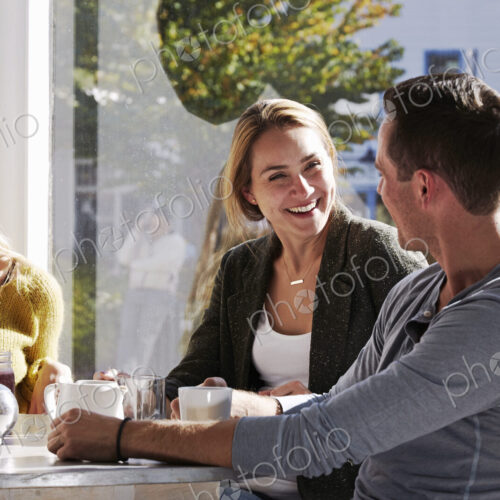 Three people sitting at a table talking, with mugs and jars of smoothies. Three people sitting at a table talking, with mugs and jars of smoothies.