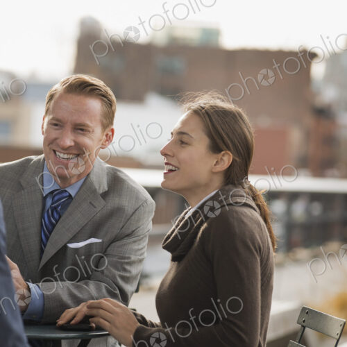 Three people standing in an open space between city buildings, talking to each other.… Three people standing in an open space between city buildings, talking to each other.…