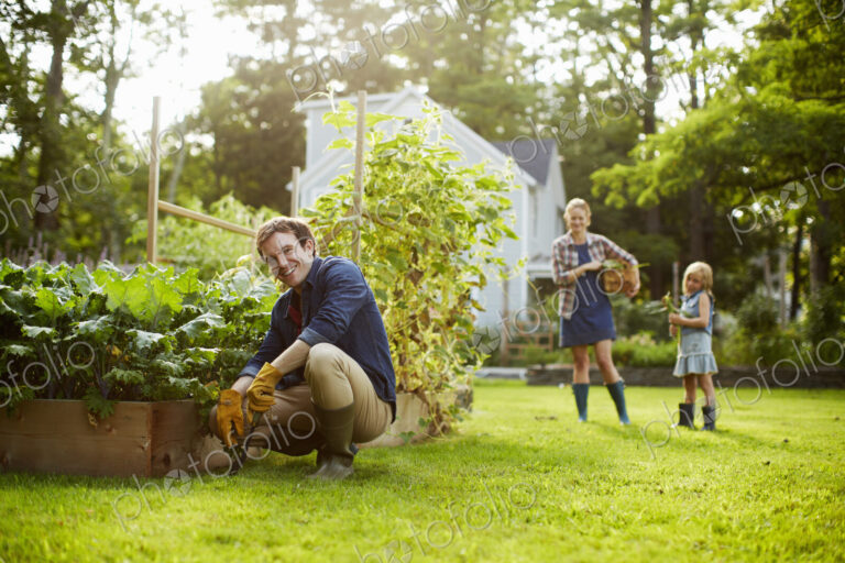Three people, two adults and a child in a vegetable garden.