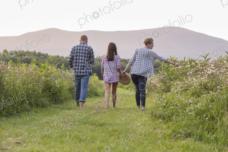 Three people walking on a mown path in a meadow